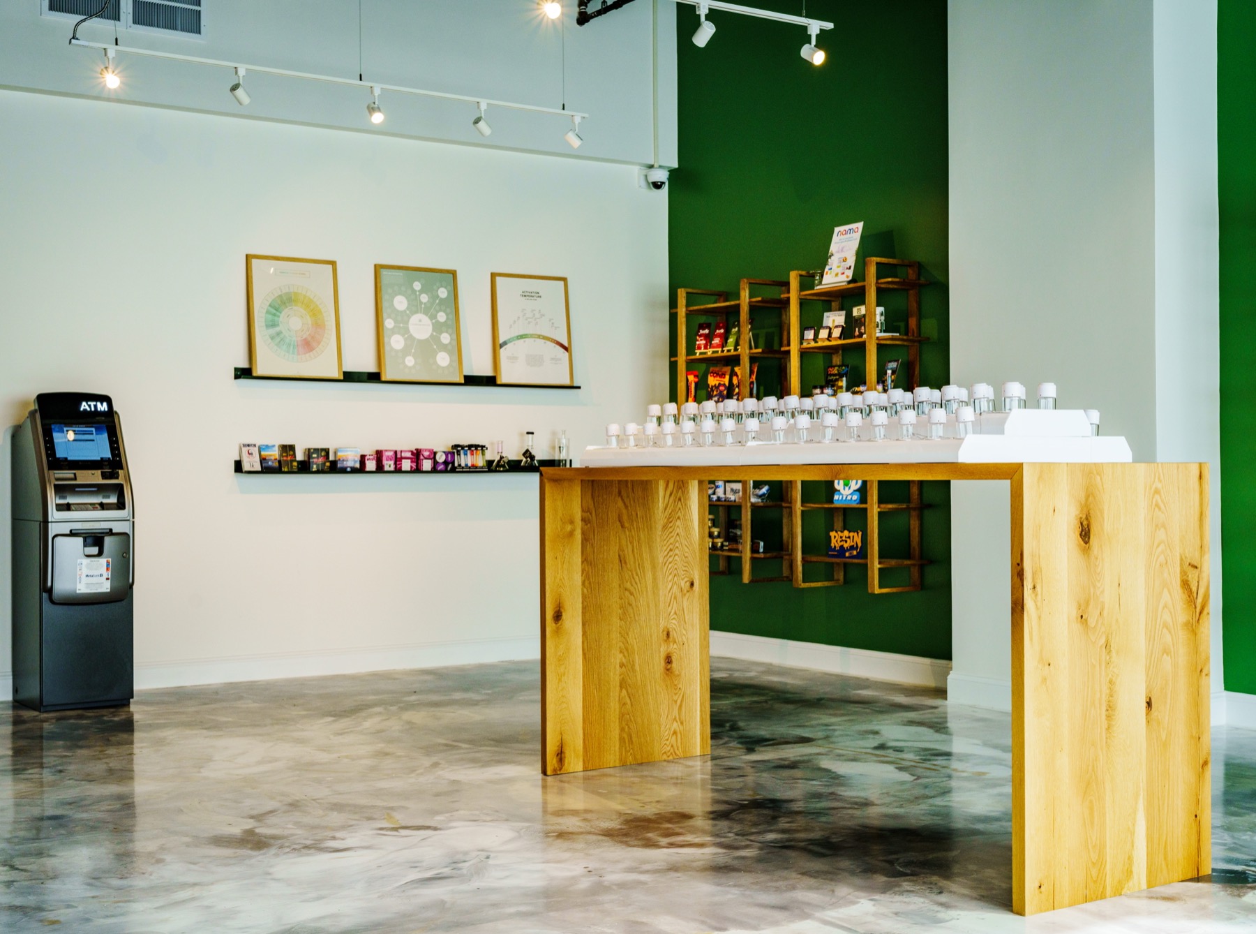 The Highline sales floor, light oak display table, white walls, botanical art in gold frames